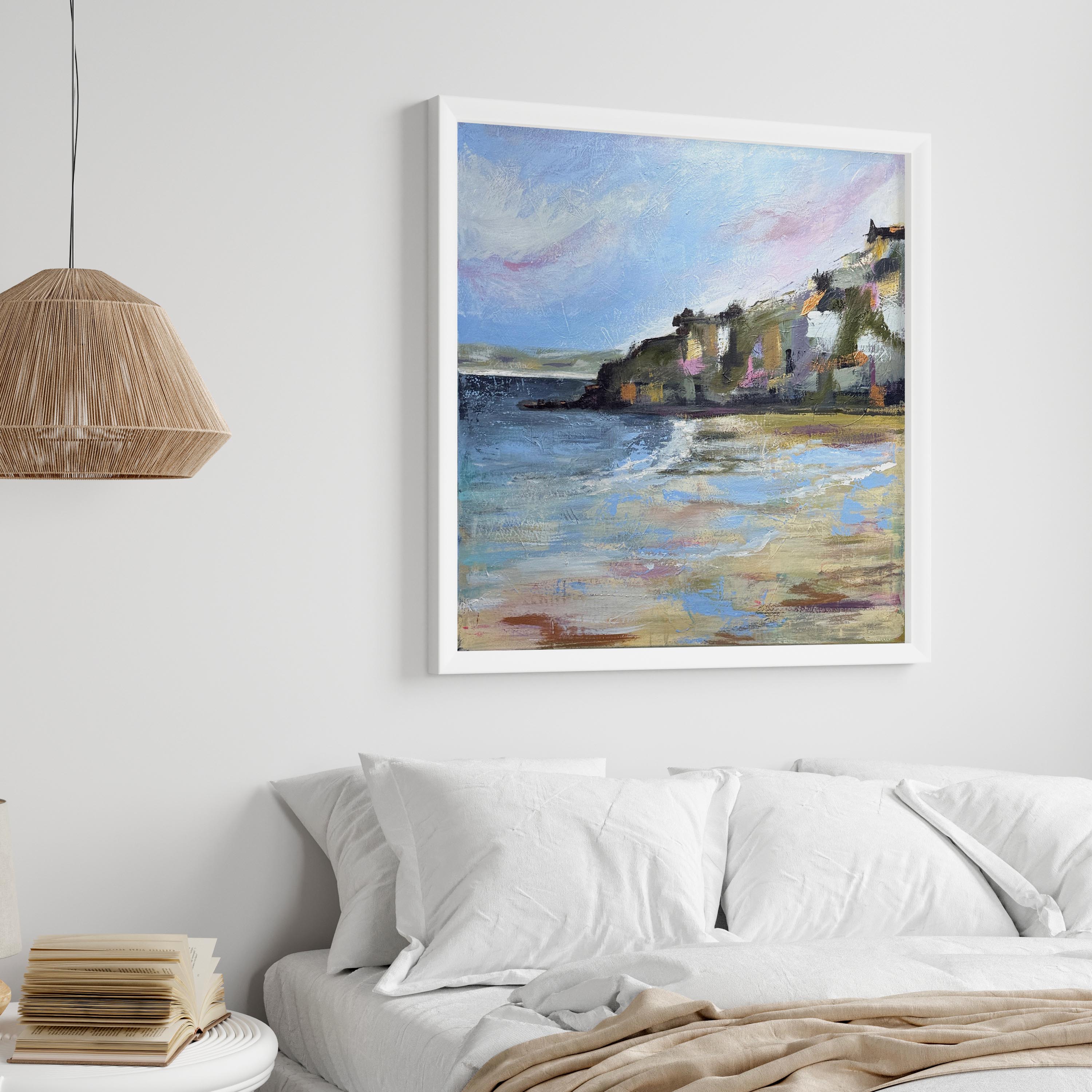 Framed painting of a coastal scene above a bed in a bedroom.