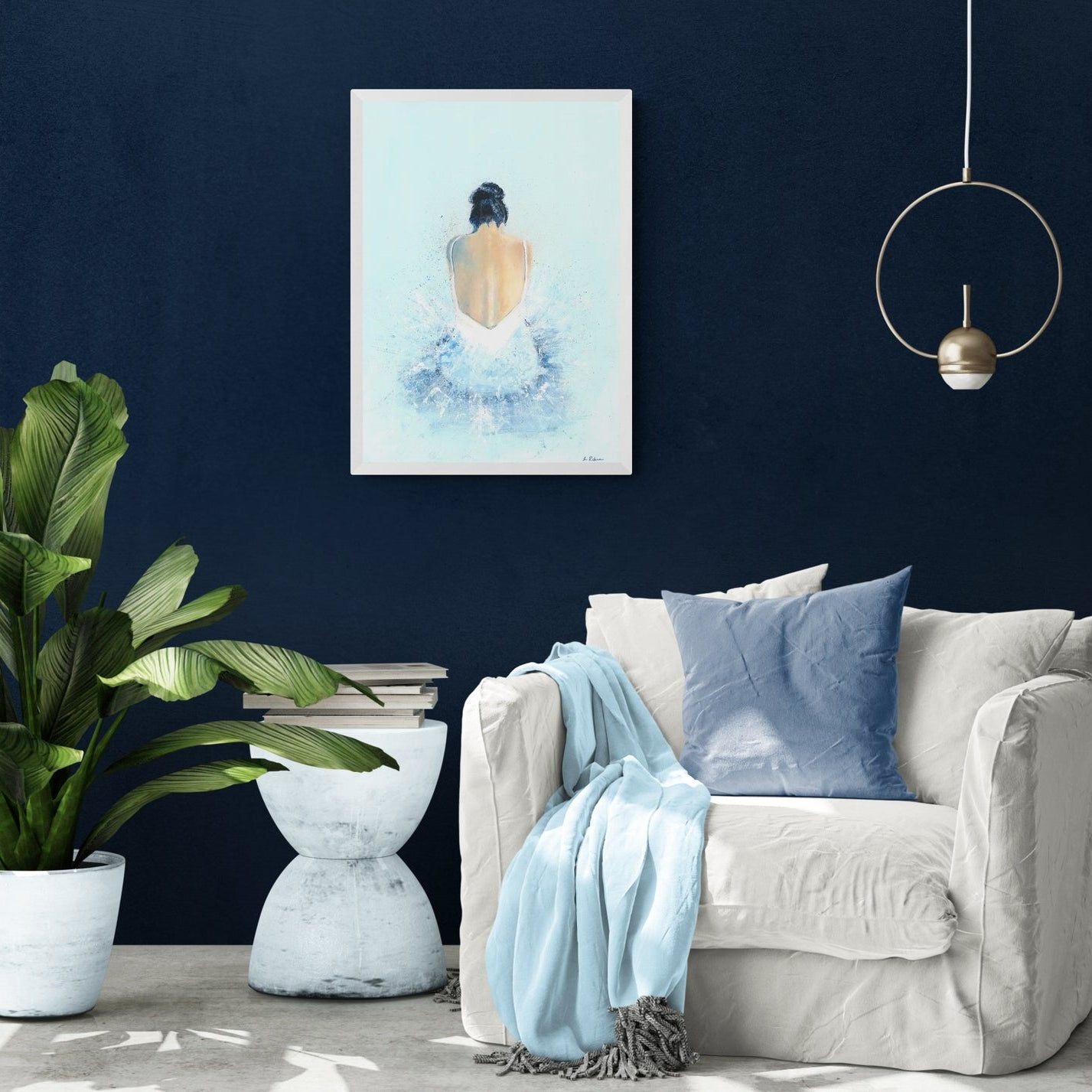 A print of an acrylic painting of a woman sat on the floor wearing a tutu. The painting is on a dark blue wall in a living room setting with a cream sofa and a potted plant